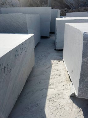 Beyaz mermer bloklar kusursuz bir şekilde kesilmiş ve bir taş ocağında hizalanmış, tam ışık altında alınmış.. 