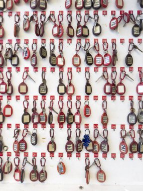 Beyaz arka planda düzgünce asılı duran numaralandırılmış anahtarlıklar, tipik bir resepsiyon alanı.. 