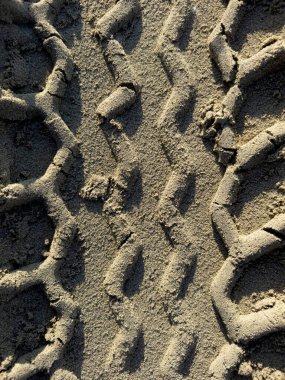 Üç boyutlu geometrik desenlerin yakın plan ayrıntıları kumlu bir yüzeydeki lastik izleriyle oluşmuştur.. 