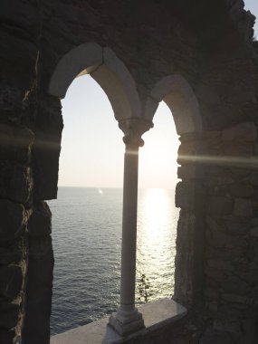 Günbatımında Ligurian Denizi 'ni çevreleyen antik taş bir pencereden Portovenere' deki pitoresk bir yerden görüntüyü izle 
