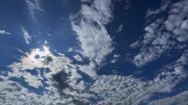Güneşin sıcak ışıklarıyla aydınlanan beyaz bulutlu berrak bir gökyüzünün hızlandırılmış videosu. 
