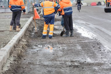 Tamirat sırasında, bir grup yol işçisi bir sonbahar günü yol kenarına kaldırım döşüyorlar..