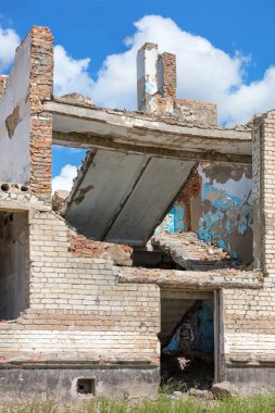 Aftermath of a bomb dropped on a school after Russian military air attacks against of background blue sky and white clouds. Vertical image.