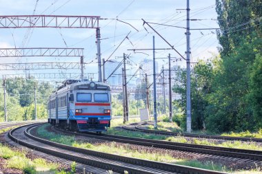 Passenger electric train delivers passengers from the suburbs to the city by rail, on a summer sunny day.