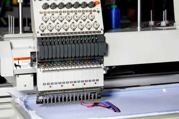 A fragment of an electronic industrial embroidery machine with a tension mechanism for embroidering with multi-colored threads. Selective focus. Copy space.