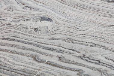 Çapraz dalga damarları, çizgileri ve benekleri olan dumanlı gri granit dokusu.