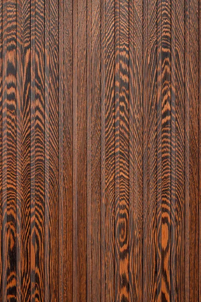 The natural wood texture of rich chocolate color on decorative vertical stripes of tiger wood with a characteristic pattern.