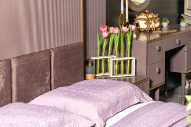 Yatağın başında, komodinin üzerinde cam şeffaf test tüplerinden yapılmış vazolarda taze açan kırmızı laleler var. Minimalist yatak odası iç tasarımı kavramı. Boşluğu kopyala.