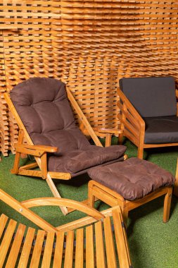 Yumuşak yastıklı rahat ahşap koltuklar şık bir tahta duvarın arka planında dinlenmek için. Dikey resim.