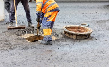 Turuncu ve mavi tulumlu bir yol işçisi ekibi at arabasındaki lağım çukurunu tamir ediyor. Boşluğu kopyala.