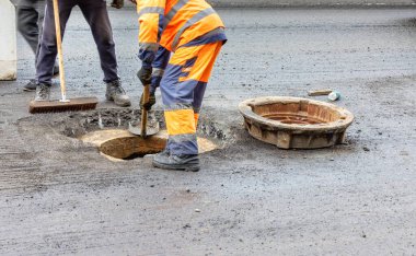 Turuncu ve mavi tulumlu bir yol işçisi ekibi at arabasındaki lağım çukurunu tamir ediyor. Boşluğu kopyala.