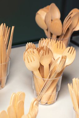 Çevre dostu tek kullanımlık mutfak aletleri. Plastik bardakta yuvarlak ahşap çatallar. Ekoloji, sıfır atık kavramı.