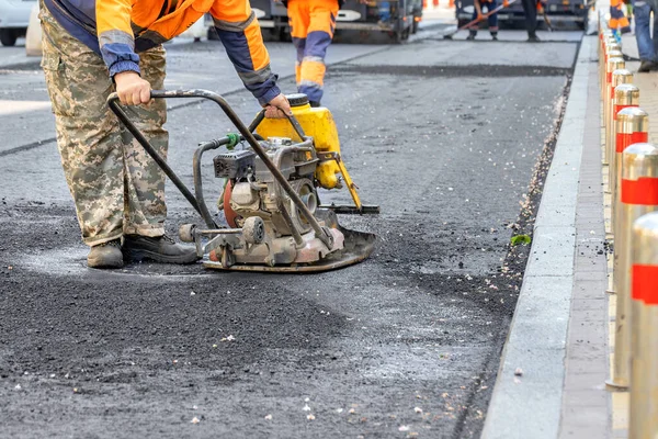 Trabalhador Estrada Repara Uma Seção Estrada Compactando Asfalto Fresco Com — Fotografia de Stock