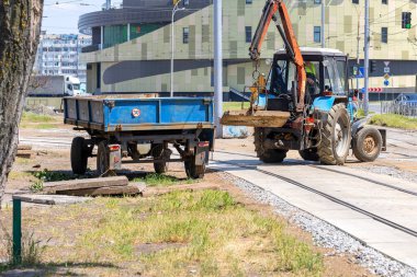 Eski bir traktör, şehir tramvay raylarının inşası ve yenilenmesinden sonra eski beton levhaları metal bir karavana yüklüyor. Şehrin gelişim konsepti. Boşluğu kopyala.