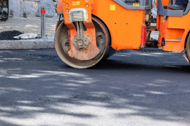 Asfalt beton işçiliğinde ağır titreşimli silindir. Tekerleğin bir parçası, bir şehir yolu yapım aşamasında, asfaltlama devam ediyor. Boşluğu kopyala.