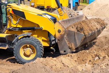 Toprak çalışmaları, büyük metal bir kova kullanarak bir traktör buldozeriyle yürütülür..