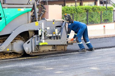 Bir asfalt kaldırıcısının çalışma sürecinin bir parçası bir yaz günü şehir yolunda bir işçi tarafından ayarlanmış. Boşluğu kopyala.