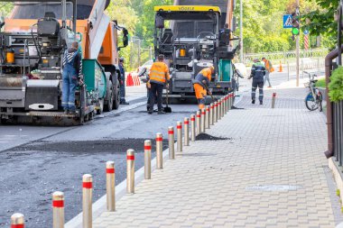 Yol yapımcıları tarafından işletilen sanayi kaldırımları bir bahar günü şehrin sokaklarına asfalt döşeyen bir yolu onarıyor. Uzayı kopyala - 05. - 20. 2023. Kyiv, Ukrayna.