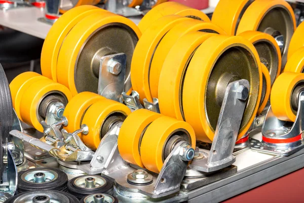 A group of industrial wheels in different sizes and diameters in warm orange tones for use in heavy duty polyurethane industrial carts with swivel rubber wheels.