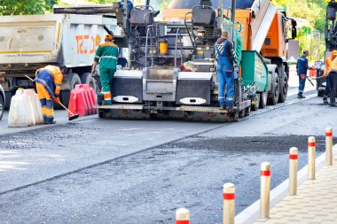 Yol yapımcıları tarafından işletilen sanayi kaldırımları bir bahar günü şehrin sokaklarına asfalt döşeyen bir yolu onarıyor. Uzayı kopyala - 05. - 20. 2023. Kyiv, Ukrayna.