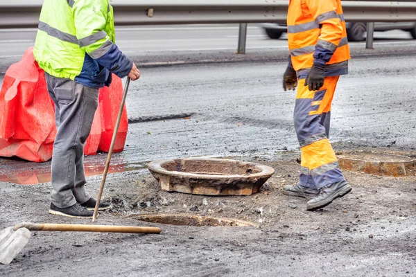 Workers of the water utility and road maintenance service change sewer manholes on the carriageway.