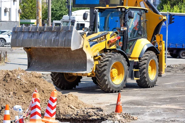 Güneşli bir günde yol çalışması alanında büyük bir hidrolik kaydırak kovası olan bir traktör. Boşluğu kopyala.