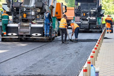 Yol işçileri bir yaz günü bir şehir caddesinde asfalt bırakmak için büyük sanayi kaldırımlarını kullanırlar. Boşluğu kopyala.