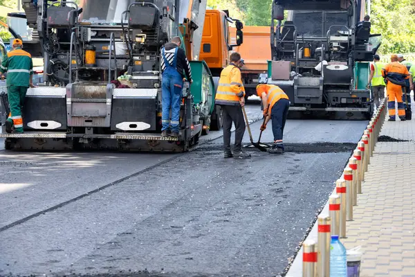 Yol işçileri bir yaz günü bir şehir caddesinde asfalt bırakmak için büyük sanayi kaldırımlarını kullanırlar. Boşluğu kopyala.