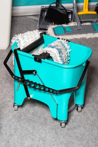 Professional turquoise bucket on wheels with a rag wringing system for wet cleaning of premises. Copy space.