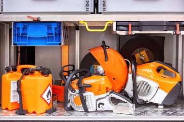 Yakıt bidonları, güvenlik ekipmanları, metal raflarda dizilmiş elektrikli testereler, profesyonel açık hava ekipmanları konsepti için hazırlanmış.