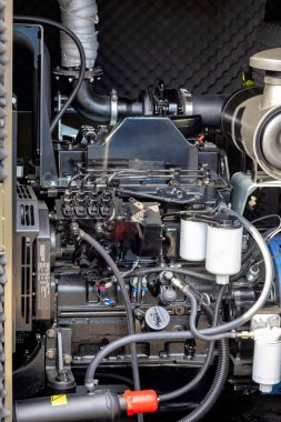Endüstriyel bir çalışma alanının derinliklerinde, sağlam bir dizel motor sergileniyor, boru ve konnektörlerden oluşan bir ağ içeriyor..