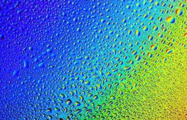 Pürüzsüz bir cam yüzeydeki karmaşık su damlacıklarıyla parlak mavi ve sarı gölgelerin büyüleyici bir görüntüsü geliştirilir. Işık çok güzel kırılır, sanatsal bir illüzyon yaratır..