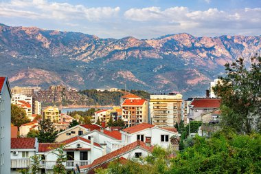 Tepelere yerleşmiş, büyüleyici evler Budva 'nın terasotta çatılarını görkemli dağlara karşı sergiliyor..