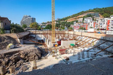 İnşaat işçileri özenle şehir manzaraları ve dağlarla çevrili yeni bir yapı inşa ediyorlar..