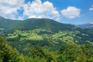 Yuvarlanan tepeler canlı yeşillikler ve ağaçlar sergiliyor, sakin bir manzara yaratıyor. Yumuşak bulutlar, açık gökyüzünde tembelce süzülerek kırsal İtalya 'nın barışçıl özünü yakalıyor..