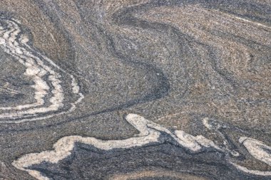 Karmaşık desenler, doğal taşa benzeyen gri ve fildişi kıvrımlar gösteren bir yüzeyden ortaya çıkar..