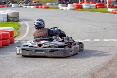 Yarışçı, canlı kırmızı ve beyaz bariyerlerle çevrili dolambaçlı bir go-kart pistinde ustaca yol alır..