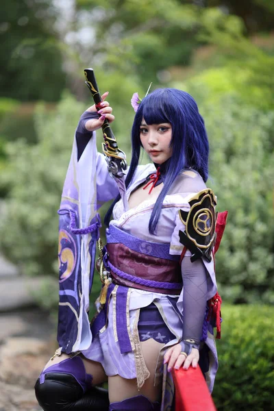 日本花园里一个穿着武士服装的年轻漂亮女子游戏的肖像 — 图库照片