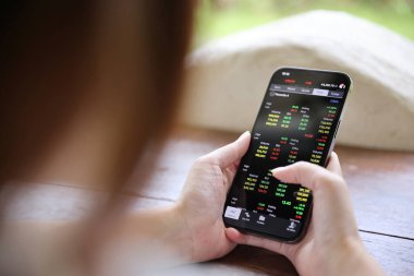 Kafede borsa alım satımı için akıllı telefon kullanan bir kadın, iş konsepti.