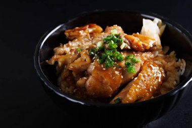 Izgara tavuk teriyaki pilavı Japon yemeği siyah arka planda izole edilmiş.