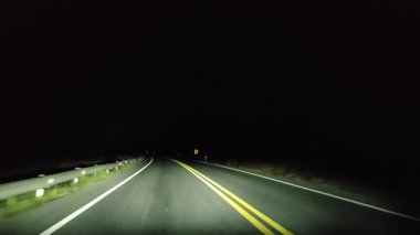 Gece kırsalda araba sürerken arabanın ön camına bakarak bakış açısı. 