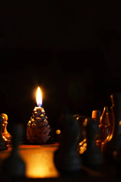 点着松果形状的蜡烛 国际象棋在前景中 手工做的假期来了黑暗背景下的蜡烛 — 图库照片