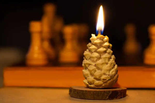 松の円錐形のキャンドルを燃焼 背景にチェス 手作りだ 休日の到来 — ストック写真