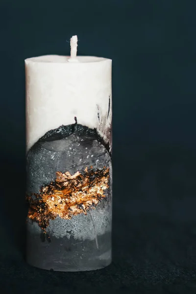 An incredibly beautiful candle on a clean background. Handmade wax and concrete candle with gilding. Holiday advent. Cozy atmosphere