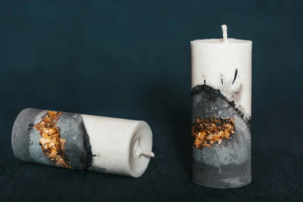 Incredibly beautiful candles on a clean background. Candles handmade from wax and concrete with gilding. Holiday advent. Cozy atmosphere