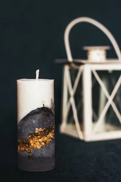 A beautiful candle on the background of an old lamp. Handmade wax and concrete candle with gilding. Holiday advent. Cozy atmosphere