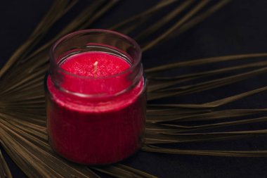 Güzel kırmızı kokulu mum ve palmiye yaprakları. El yapımı güzel bir mum. Evin rahat atmosferi.