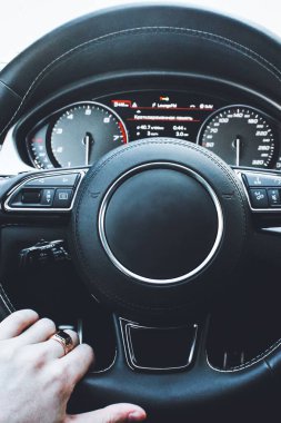 Bir adam bir lüks otomobil direksiyon simidi tutar. Elindeki altın yüzük
