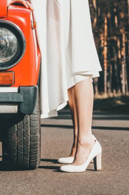 Arabanın yanında beyaz gelinlikli bir kız var. Retro araba