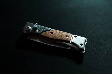 Koyu arkaplanda tahta saplı katlanmış bıçak.